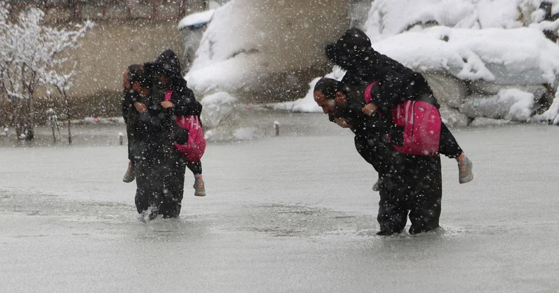 Evinin önünde biriken su nedeniyle çocuklarını sırtında taşıyor