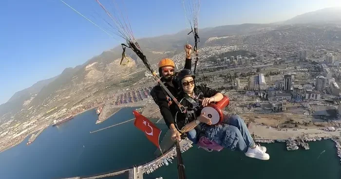 Hatay da yamaç paraşütüyle atlayan kadın gökyüzünde darbuka çaldı